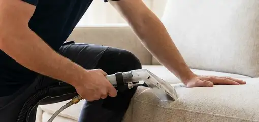 Professional upholstery cleaner deep-cleaning a fabric sofa with a handheld extraction tool, Fargo, ND.